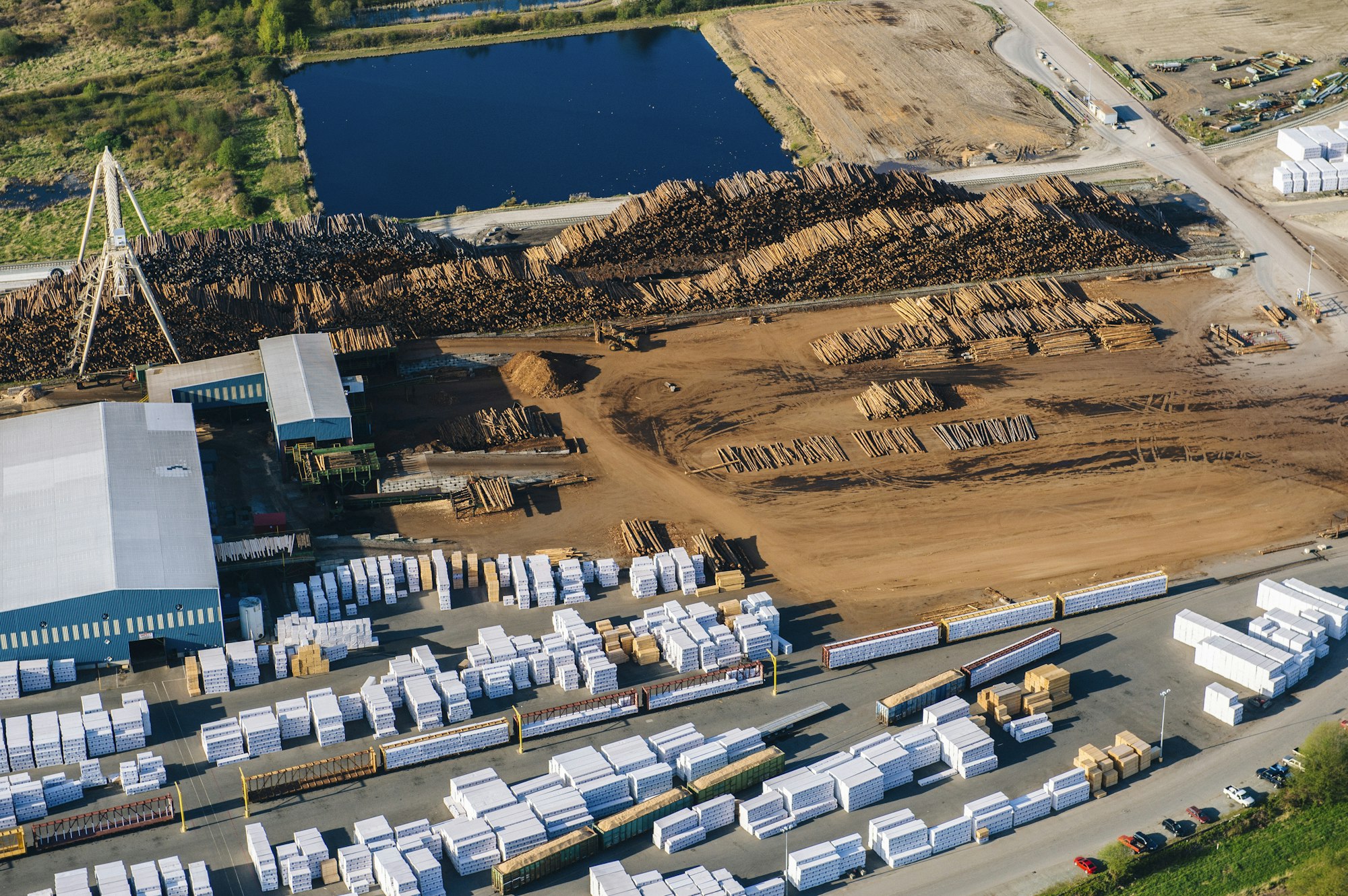 Aerial view of stacked tree trunks and warehouses in timber yard