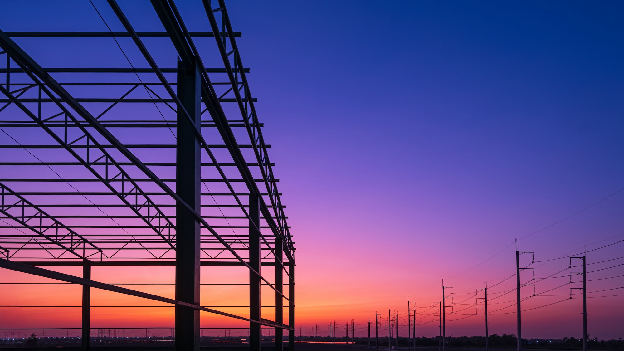 Silhouette metal framework of new warehouse building structure against colorful twilight sky